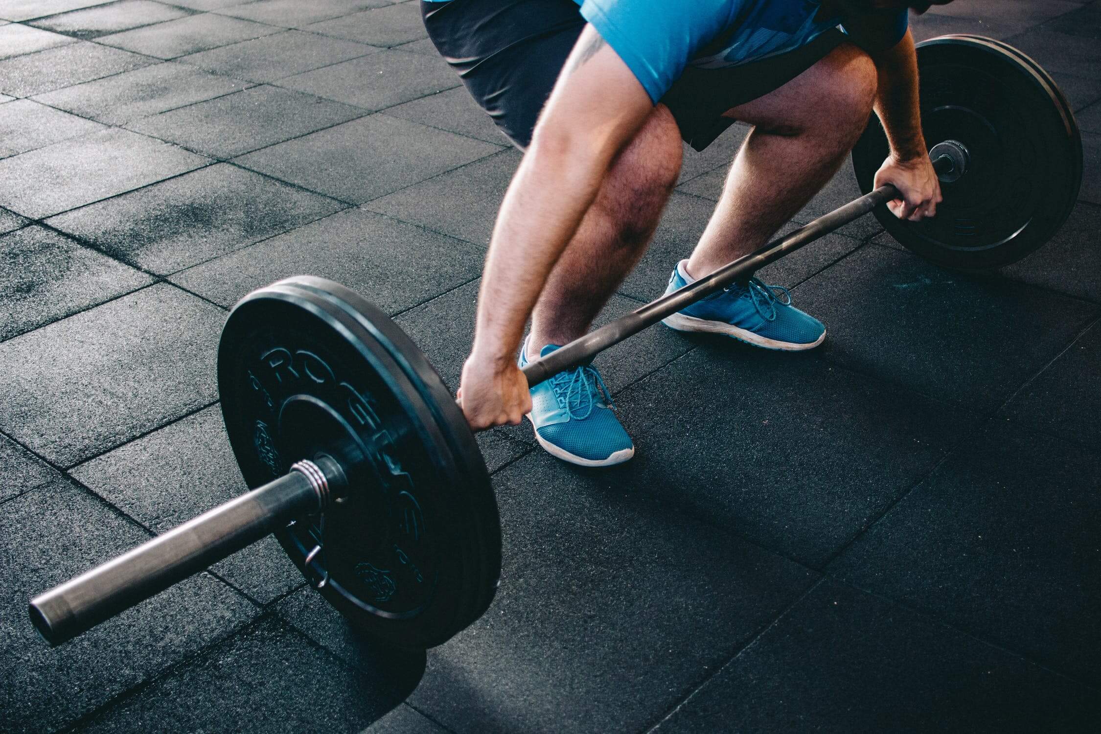 barbell on floor, person gripping bar ready to lift